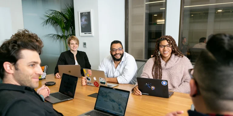 Team on laptops in a meeting comparing Odoo Community and Enterprise
